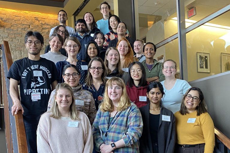 The 2024 Leadership Course instructors and alumni stand smiling on a stairwell.